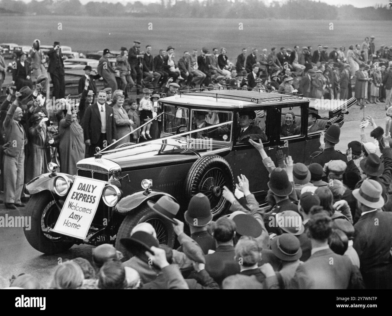 Amy Johnson winkte den jubelnden Menschenmassen zu, als sie vom Croydon-Flugplatz wegfuhr, nachdem sie den Rekord für den Rundflug zum Cape gebrochen hatte . Auf der Rückreise hat sie Tommy Rose fast zwei Tage Zeit genommen. 15. Mai 1936 Stockfoto