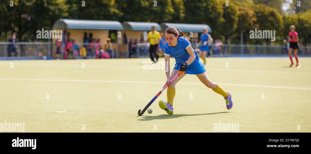 Junge Spielerin, die den Ball in einem Hockeyspiel anführt. Stockfoto
