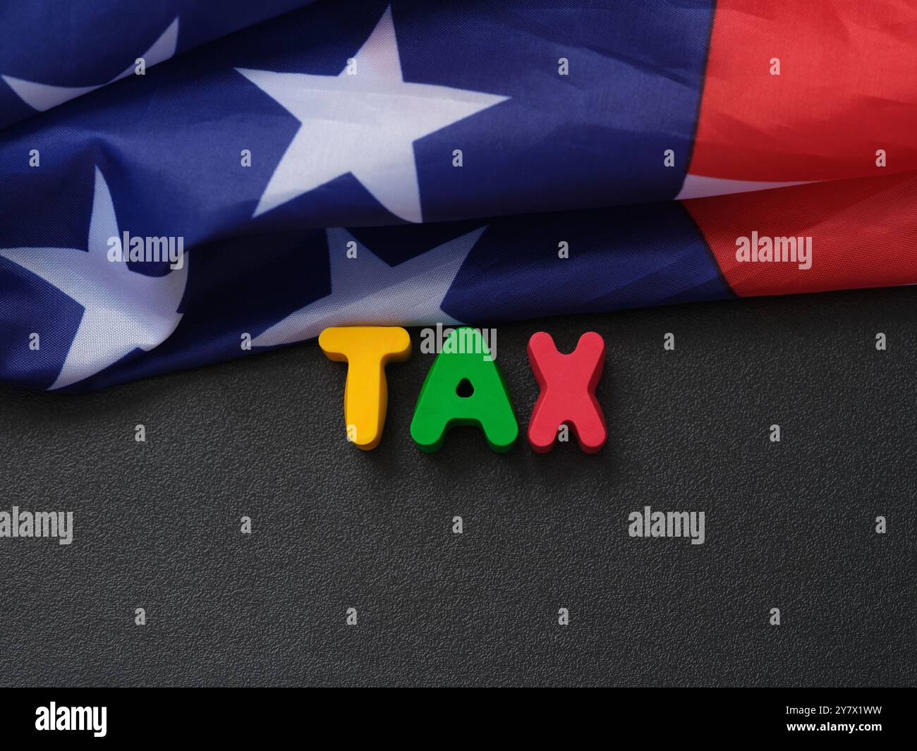 Die Flagge der USA, die auf einer Tafel liegt, mit den Buchstaben STEUER darauf. Nahaufnahme. Stockfoto