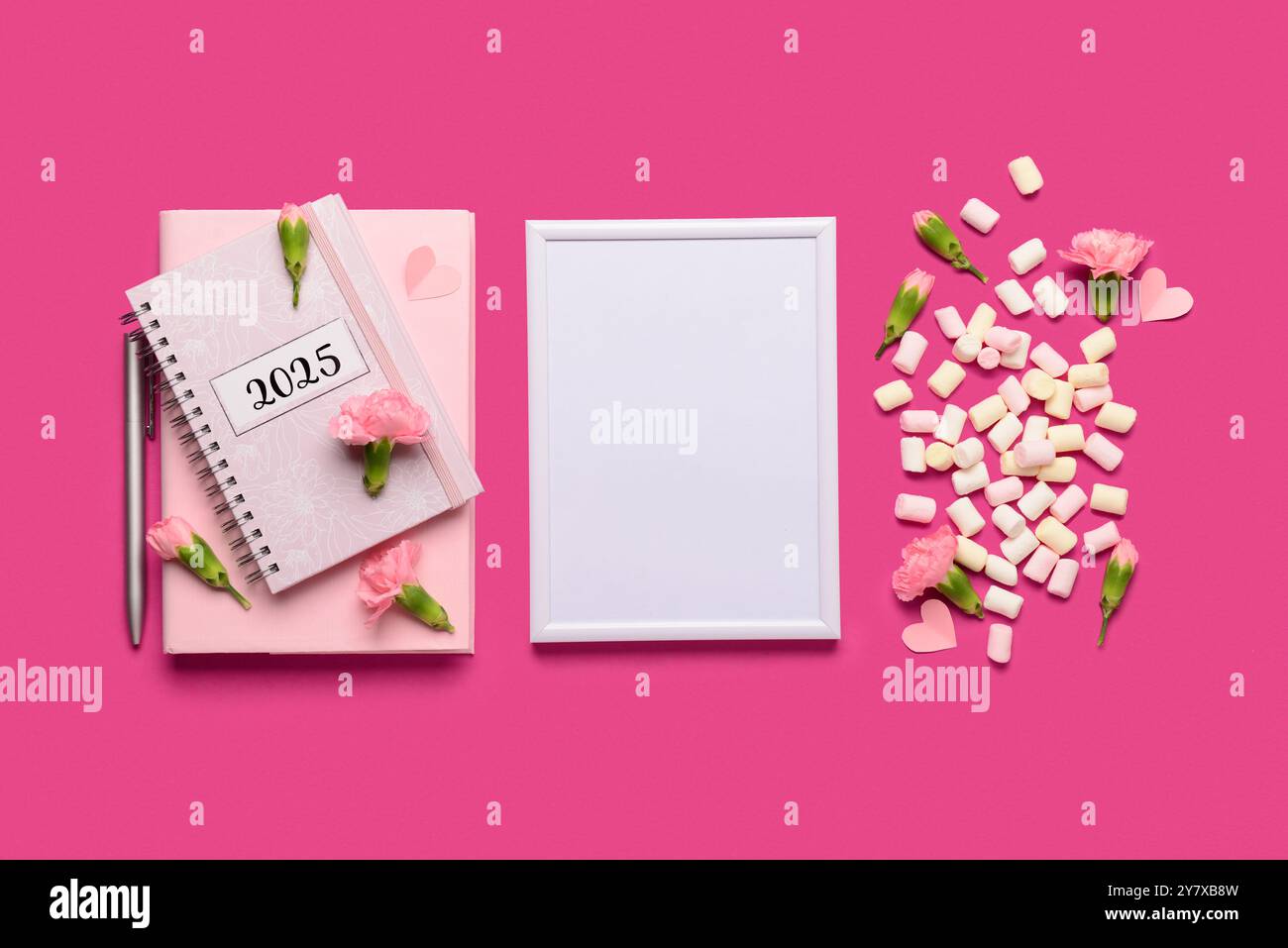 Bilderrahmen mit Notizbuch und Blumen auf rosa Hintergrund Stockfoto