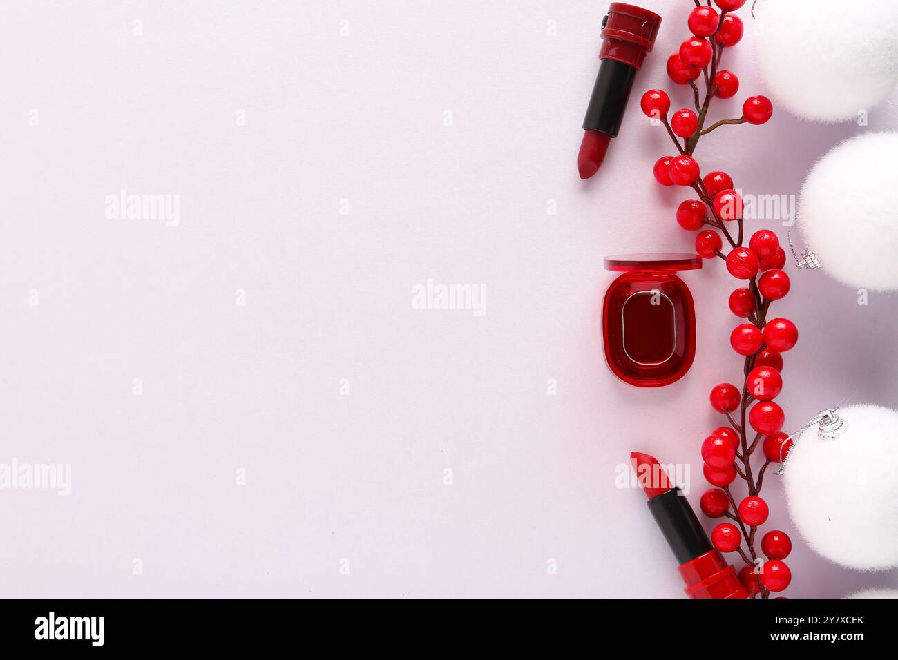 Schöne Komposition mit weißen Weihnachtskugeln, Behälter mit Lippenstift und Zweig roter Beeren auf hellrosa Hintergrund Stockfoto