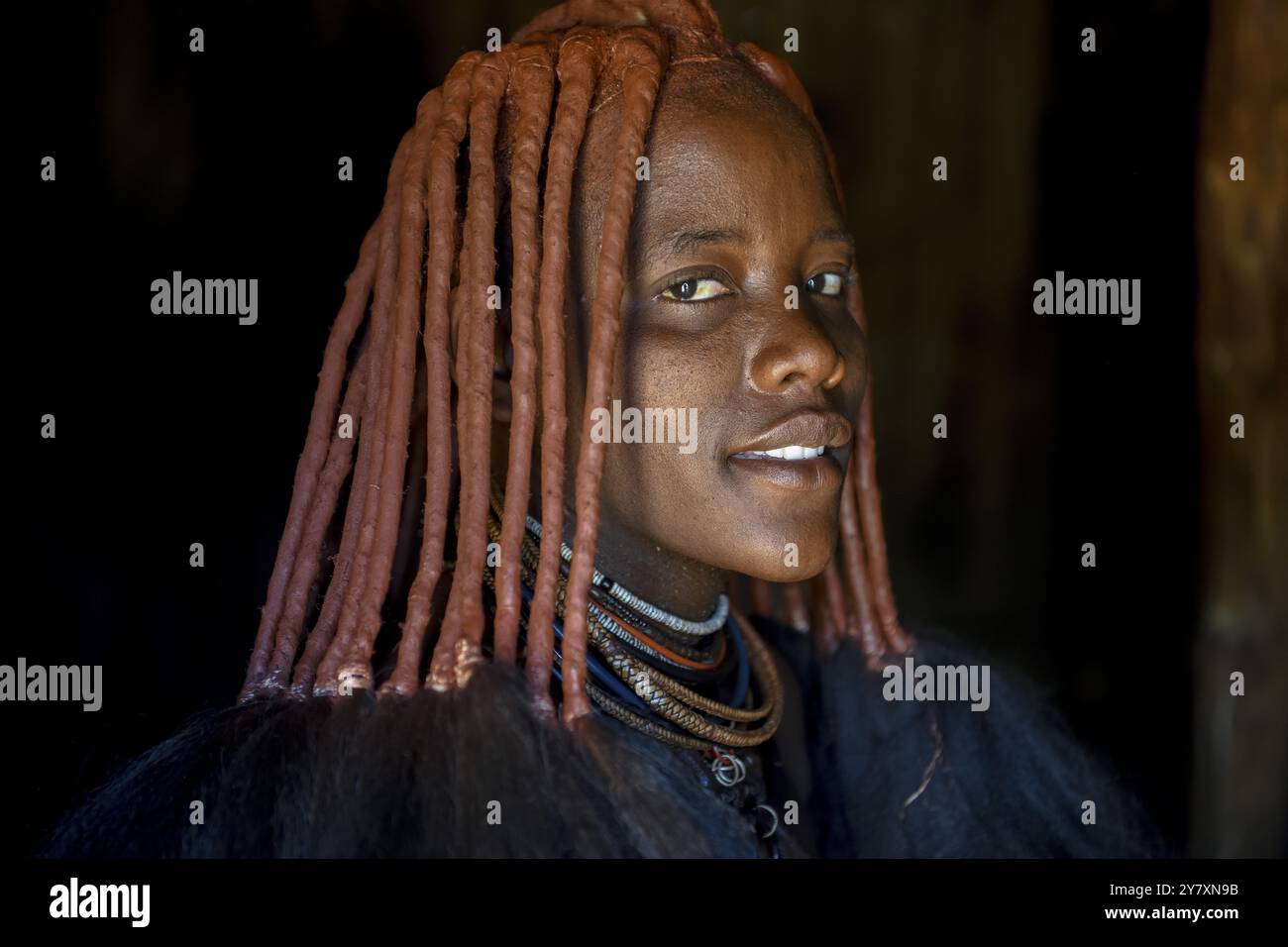 Die junge Himba-Frau in ihrer Hütte, Ohandungu, Kunene Region, Kaokoveld, Namibia, Afrika Stockfoto