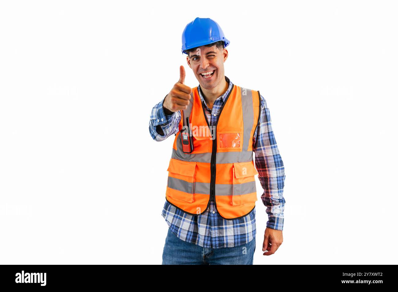 Ein zufriedener Bauarbeiter, der einen Schutzhelm und eine orangefarbene Weste trägt, hebt den Daumen mit einer Geste nach oben zur Kamera. Vermittelt einen Sinn o Stockfoto