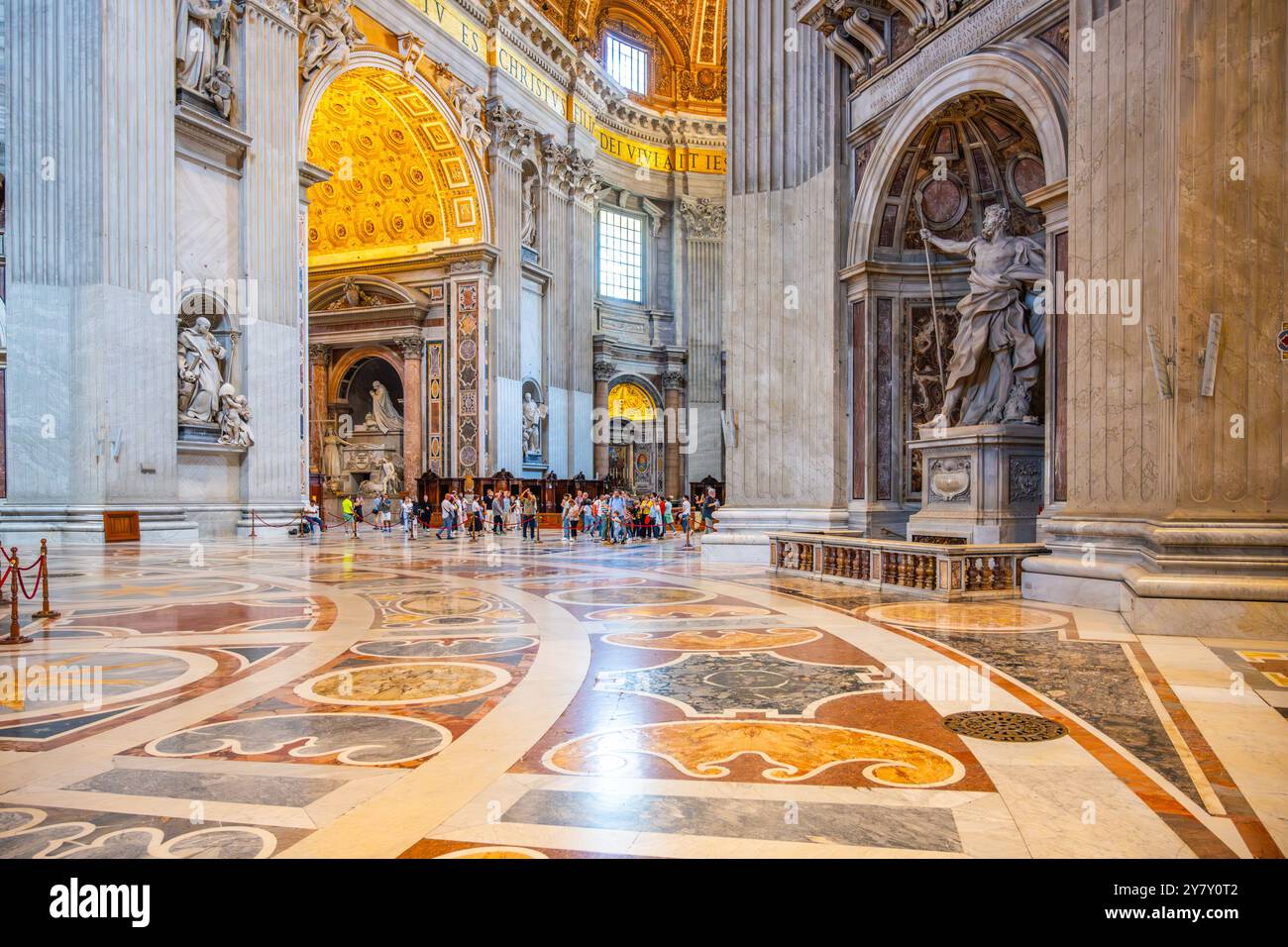 Besucher bewundern die Statue des Heiligen Longinus, die von Bernini geschnitzt wurde, im prächtigen Inneren des Petersdoms, das die Pracht der Vatikanischen Architektur widerspiegelt. Stockfoto