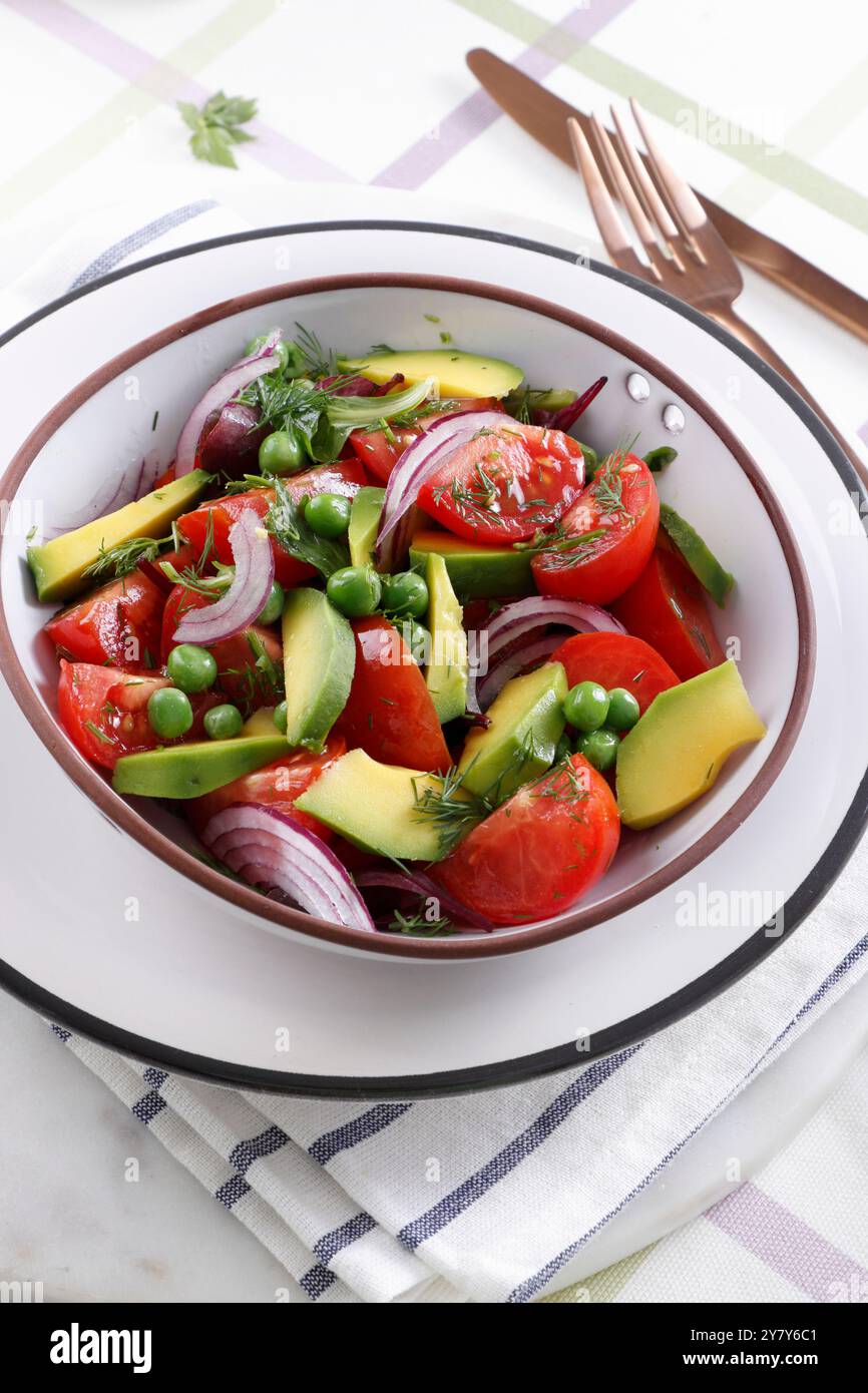 Salat mit Tomaten, Avocado, Erbsen und Zwiebeln Stockfoto