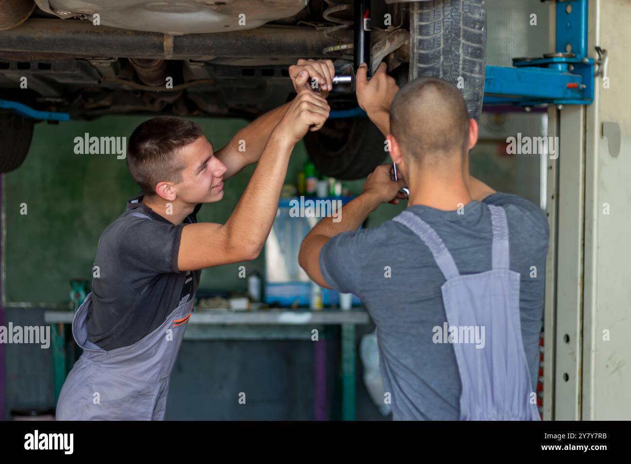Teenager-Automechaniker wechselt neue Stoßdämpfer. Austausch in der Garage Stockfoto