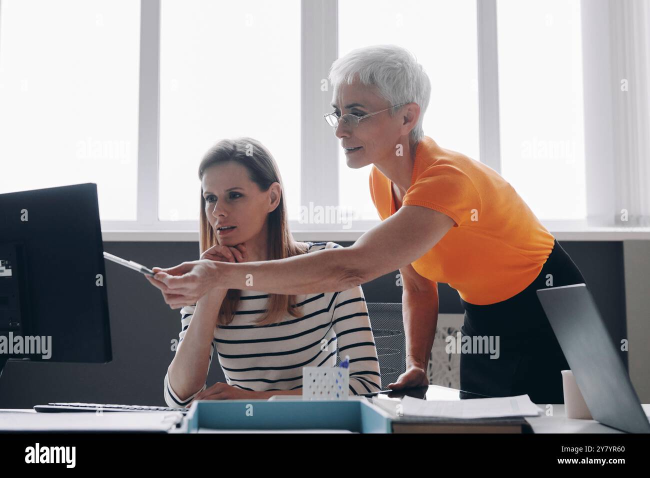 Zwei selbstbewusste Frauen diskutieren während sie gemeinsam im Büro arbeiten Stockfoto