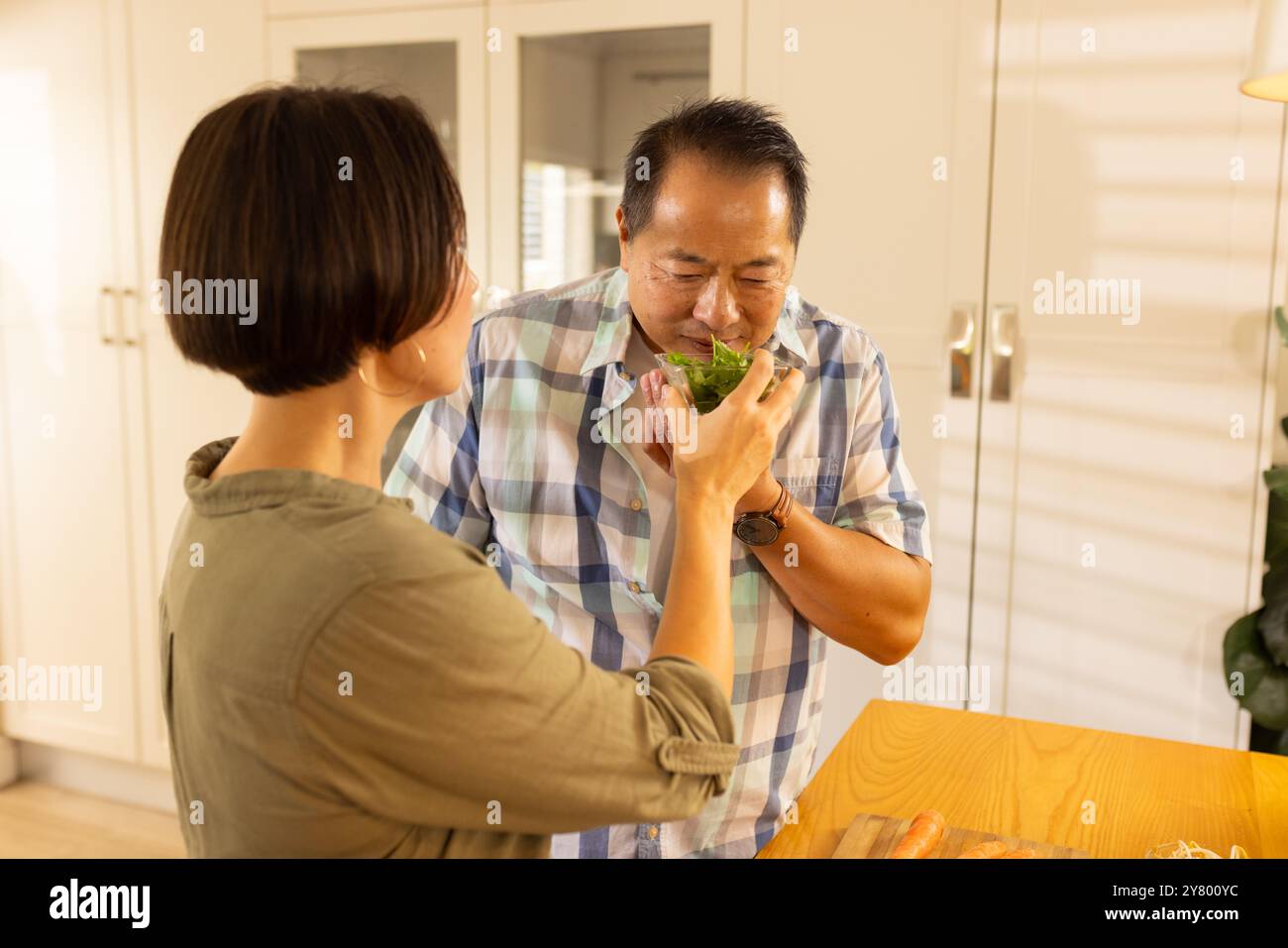 Es riecht nach frischen Kräutern, ein Paar, asiatischer Mann mittleren Alters, der das Aroma mit Frau in der Küche genießt Stockfoto