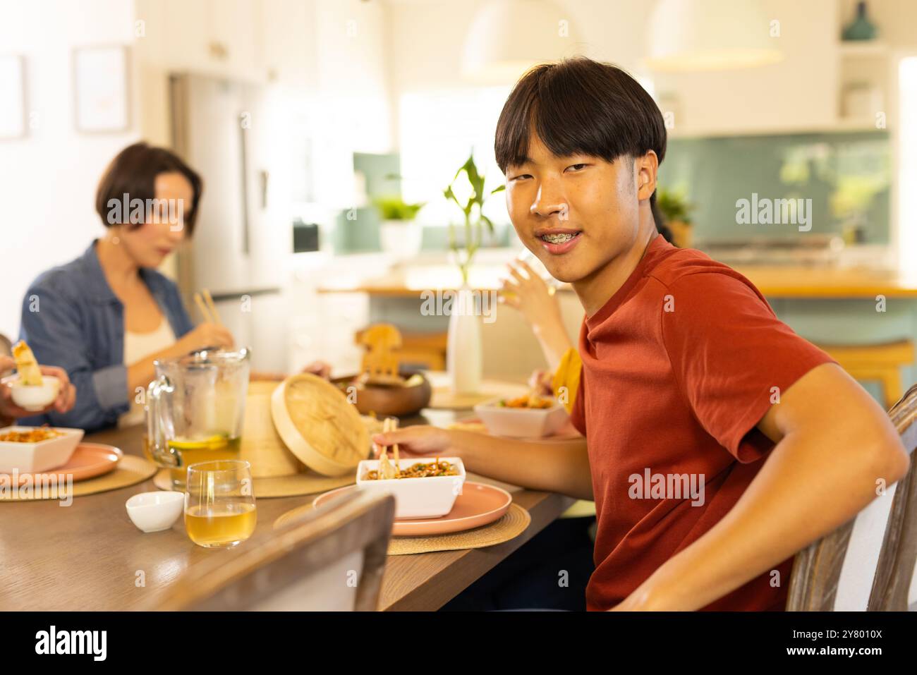 Zu Hause, Mittagessen, asiatischer Teenager lächelt mit Familie im Speisesaal in die Kamera Stockfoto