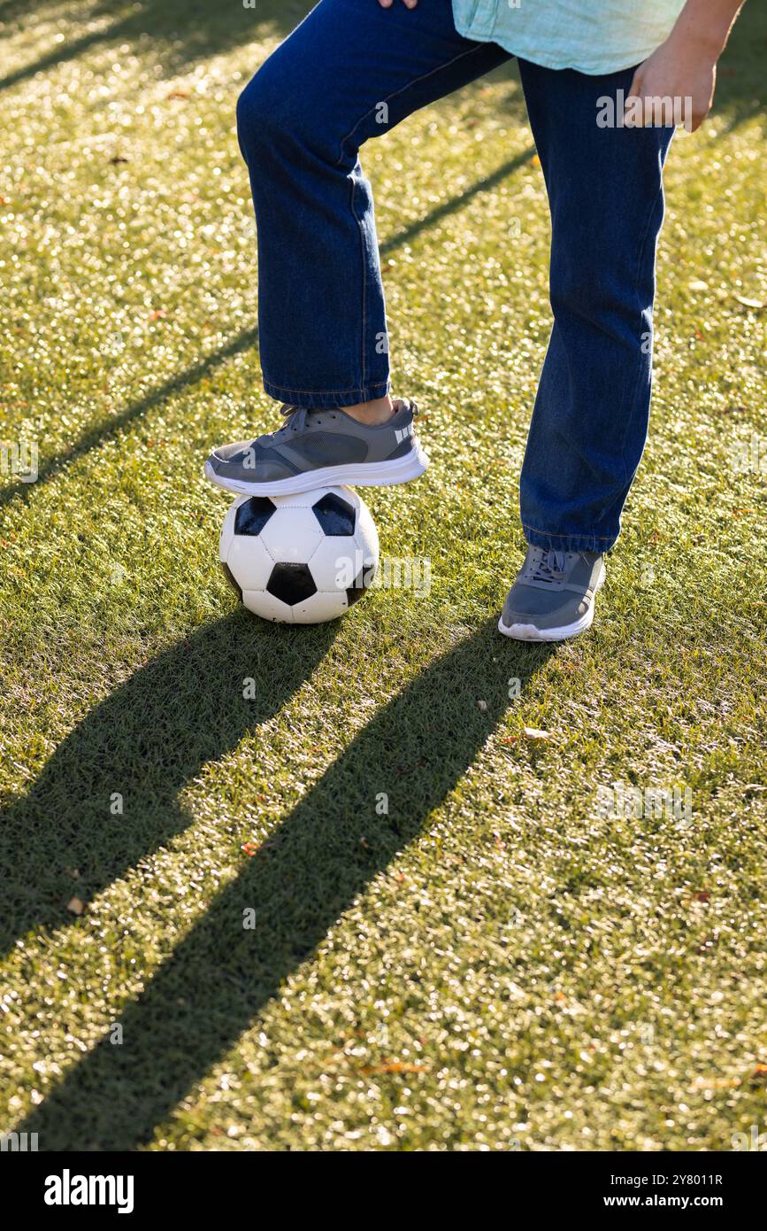 Fußball spielt, asiatischer Mann mittleren Alters, der draußen auf dem Rasenfeld mit Fuß auf Fußball steht Stockfoto