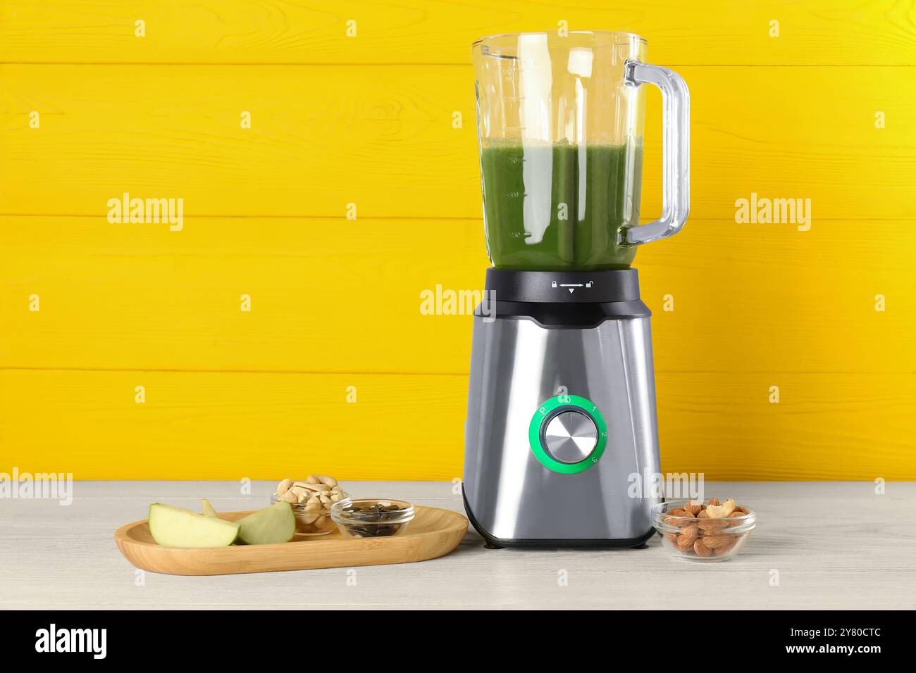 Moderner Mixer mit Smoothie und Zutaten auf hellem Holztisch. Leerzeichen für Text Stockfoto