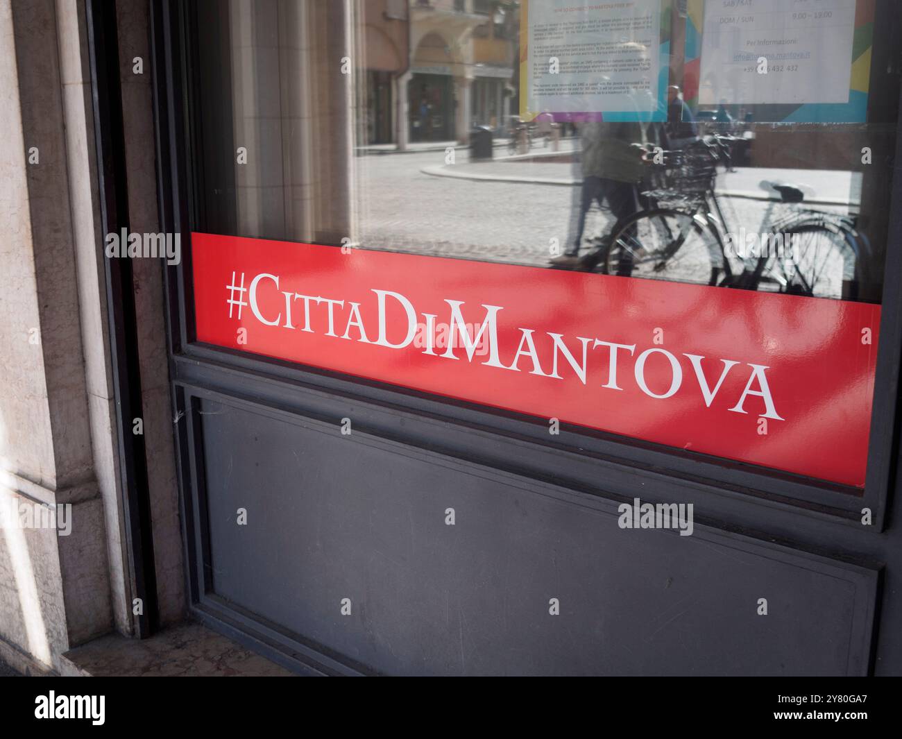 Mantua, Italien 30. September 2024 Schild des Tourismusbüros mit dem Hashtag citta di mantova spiegelt Touristen wider, die im historischen Zentrum der spazieren gehen Stockfoto