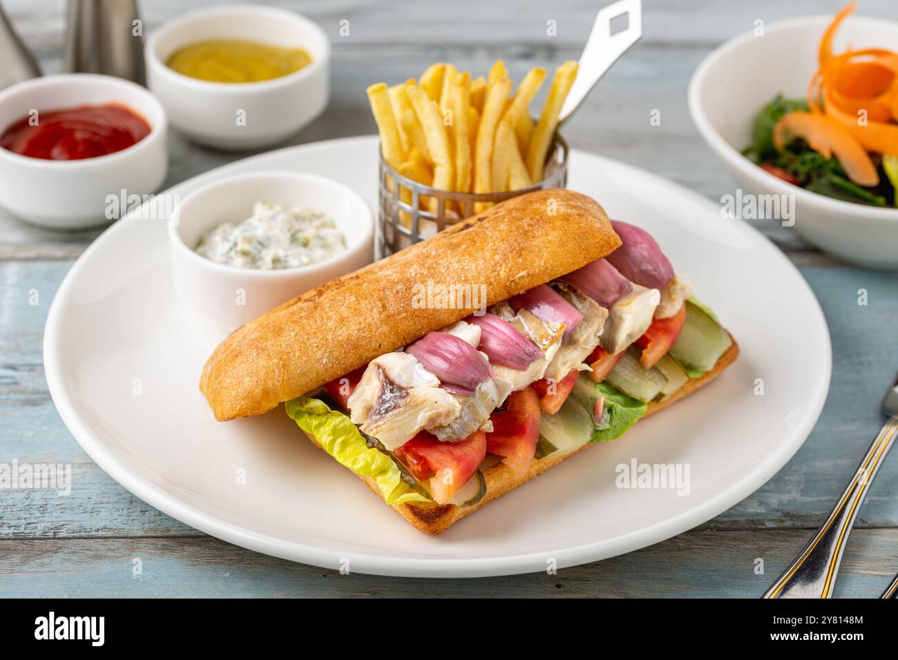 Gegrilltes Fisch-Sandwich mit roten Zwiebeln. Mit Pommes frites und Sauce Stockfoto