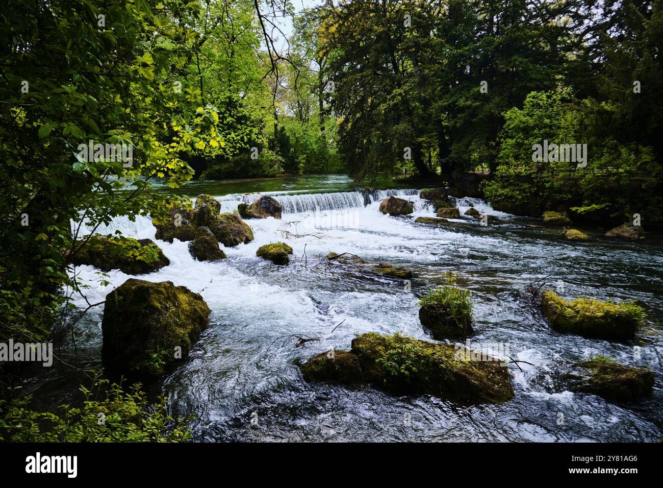 München, Deutschland - 18. April 2024: Wasserfall an einem Bach im Englischen Garten, englischer Gartenpark Stockfoto