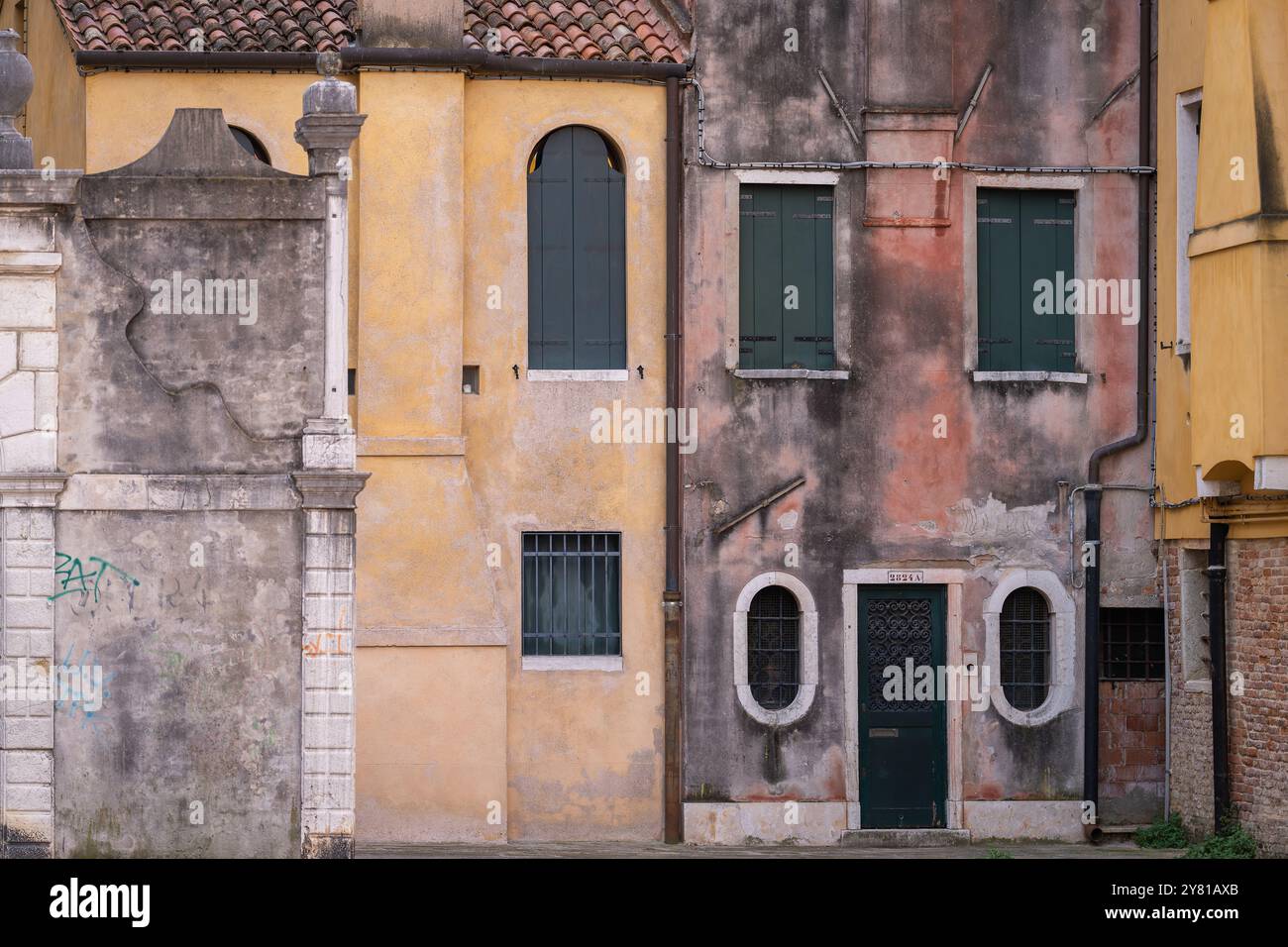 Farben von Venedig. Hintergrund mit Gipswänden und Fenstern mit geschlossenen Rollläden. Venezianisches Gelb, Petrol und staubiges Rosa. Harmonische Farben. Stockfoto