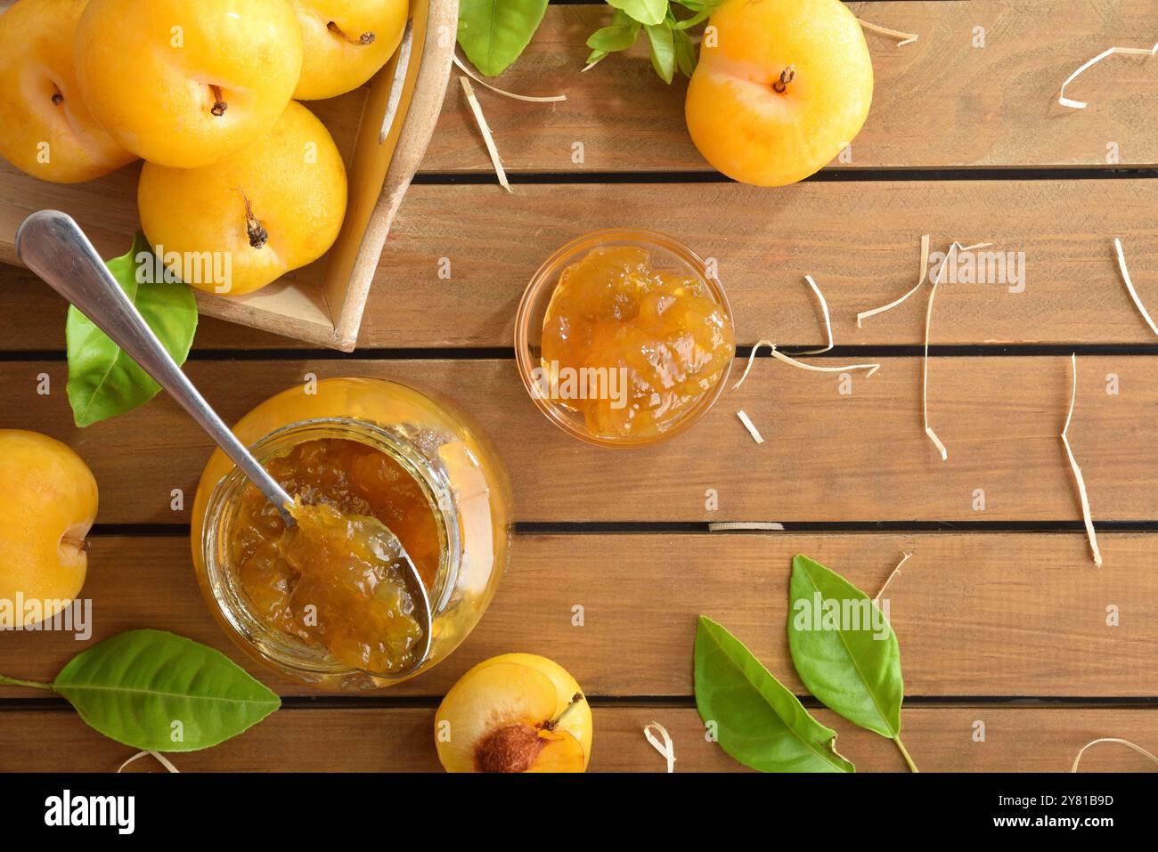 Hausgemachte natürliche Pflaumenmarmelade im Glasgefäß auf Holztisch mit Obststücken auf Tablett. Draufsicht. Stockfoto