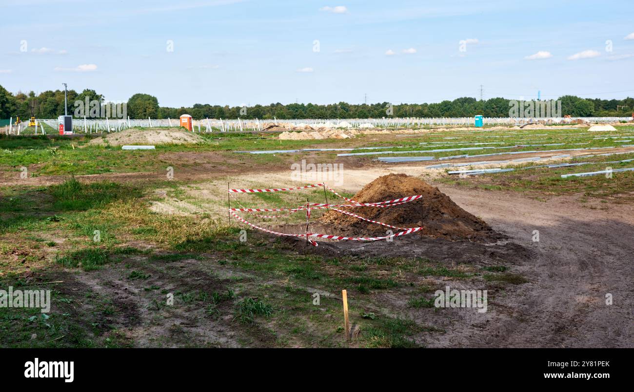 Baustelle eines Solarparks, vor einem klaren Himmel. Agrar- und Agrar-Kulturland wird für die Erzeugung erneuerbarer Energien genutzt. Stockfoto