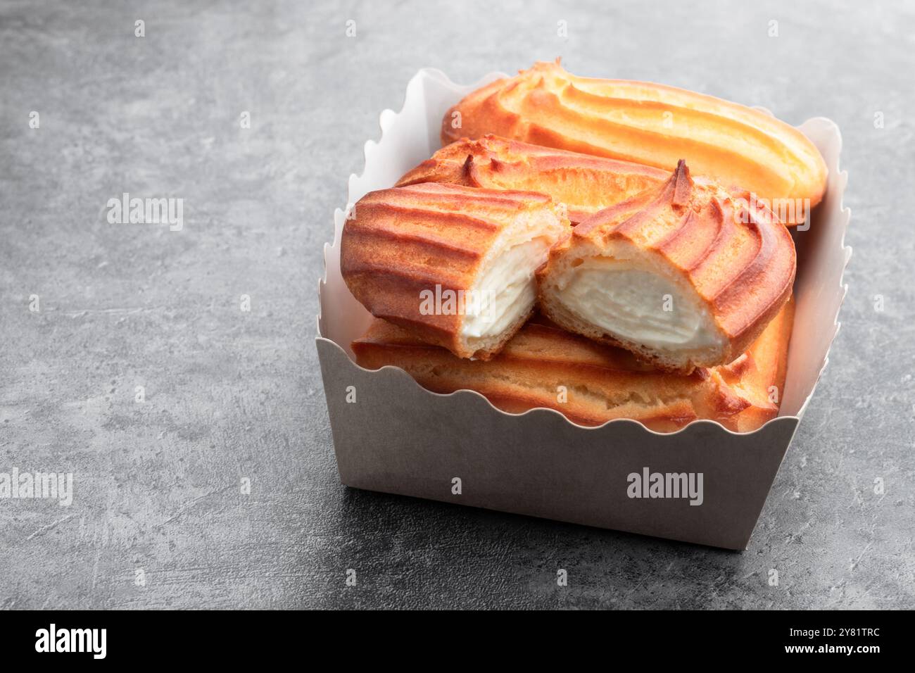 Eclairs mit Schlagsahne auf grauem Hintergrund Stockfoto Eclairs mit Schlagsahne auf grauem Hintergrund Stockfoto