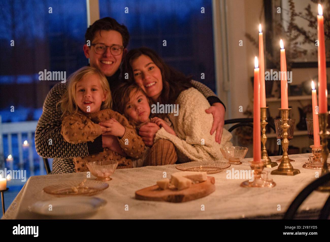 Familie genießt ein warmes Abendessen bei Kerzenschein an einem elegant gedeckten Tisch am Abend. Stockfoto