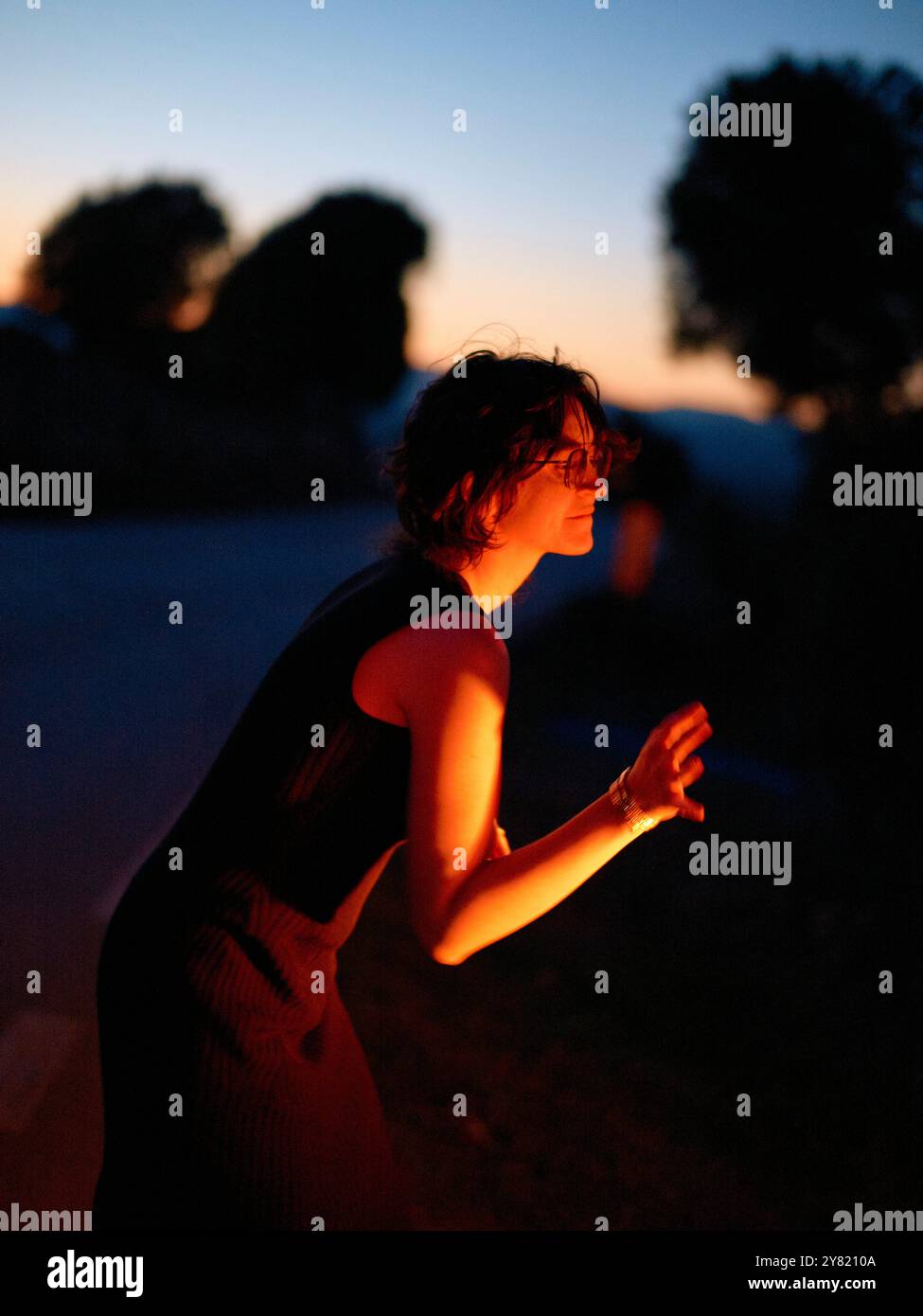 Frau in Silhouette vor einem Dämmerungshimmel, die ihre Hände klatscht. Stockfoto