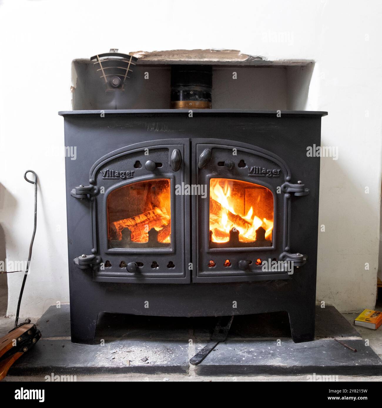 Holzfeuer brennt brennend in einem Villager Holzofen in einem Zimmer Haus Haus Haus Ferienhaus Carmarthenshire Wales Großbritannien Großbritannien 2024 KATHY DEWITT Stockfoto