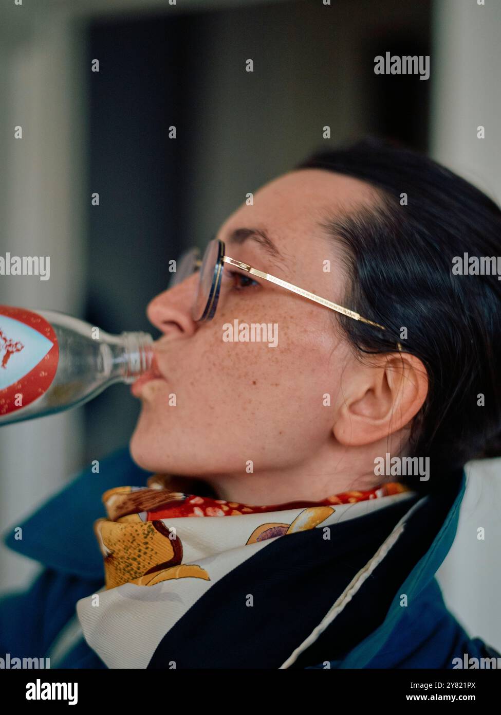 Eine Frau in Brille und Schal trinkt aus einer Limonade. Stockfoto