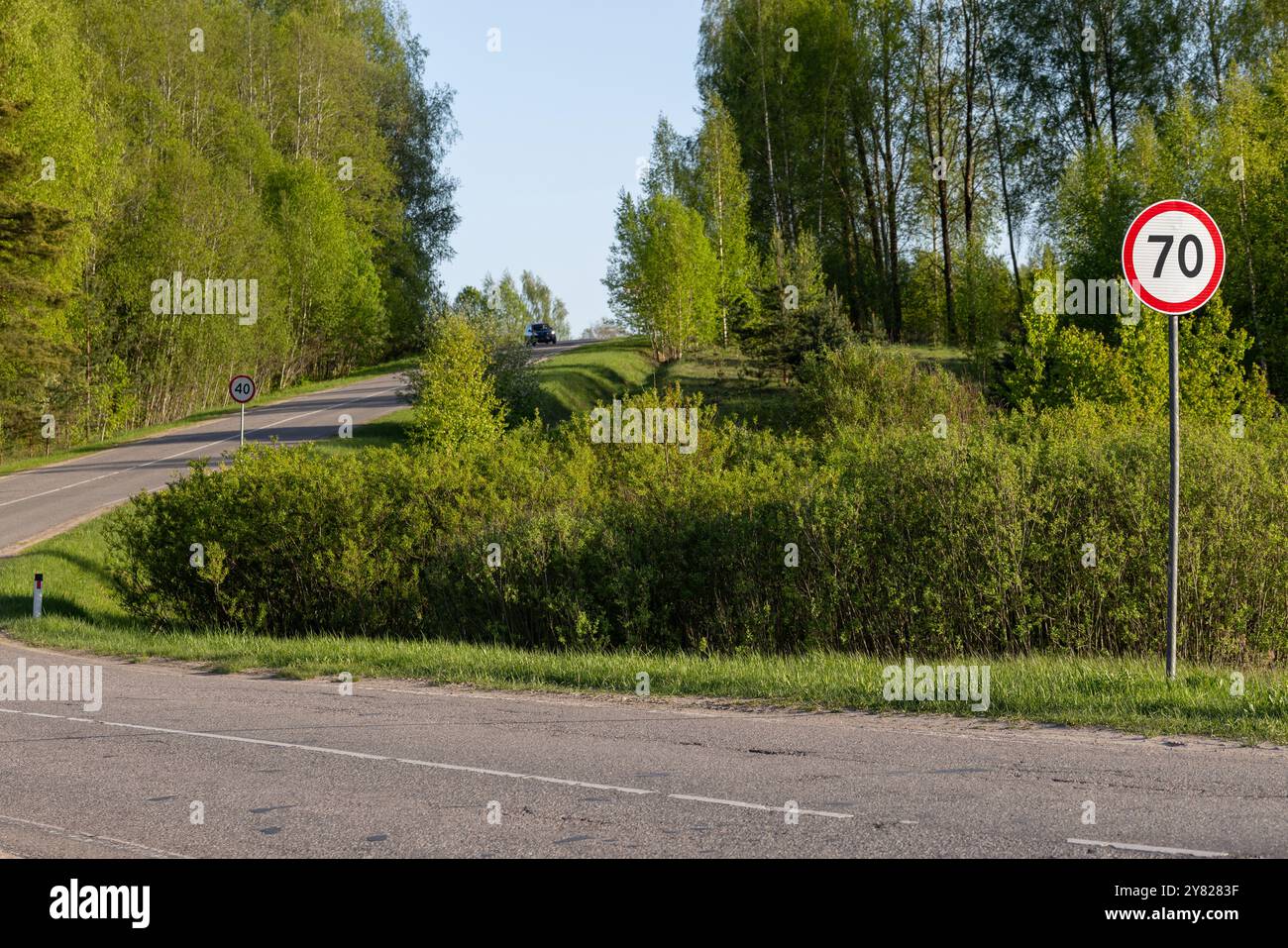 Abbiegende Landstraße mit Straßenschildern am Straßenrand Stockfoto
