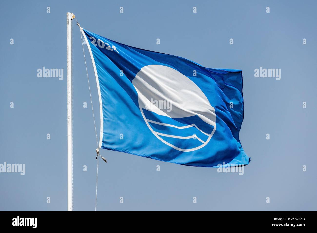 Blue Flag Beach 2024. Nahaufnahme einer Flagge, die unter blauem bewölktem Himmel winkt Stockfoto