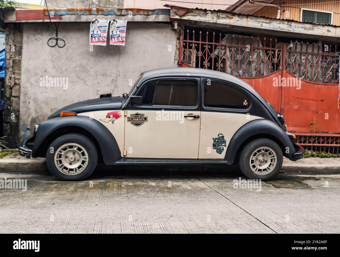 Manila, Philippinen - 27. August 2019: Ein weiß-schwarzer VW-Käfer parkt auf einer Straße vor einer Betonmauer. Stockfoto