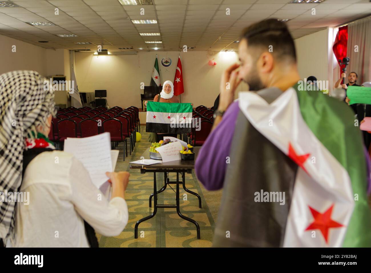 Gaziantep, Turkiye. 28. September 2023. Einige Mitglieder syrischer Gemeindeorganisationen treffen sich in der Bulbulzadeh Hall in der Innenstadt von Gaziantep, um Solidarität mit den anhaltenden regierungsfeindlichen Protesten in der syrischen Südweststadt Suweida zu zeigen. Während der Veranstaltung in der südtürkischen Stadt Gaziantep hissen einige Teilnehmer die syrische Oppositionsflagge sowie Banner gegen die nationale Koalition der syrischen Revolution und der Oppositionskräfte. Der Organisator der Veranstaltung, Ensaf Naser, argumentierte, dass die syrische Nationalkoalition die Syrer nicht repräsentiere. Während ihrer Rede kritisierte Naser die Stockfoto