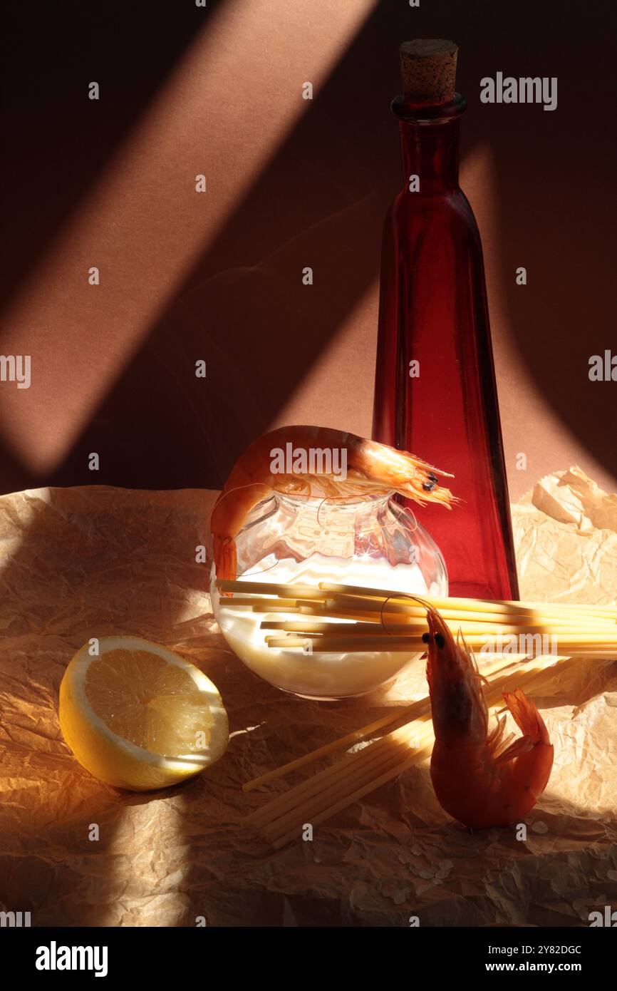 Garnelen mit Zutaten für Garnelenspaghetti: Eine rote Ölflasche, eine halbe Zitrone und eine Sahne in einer kleinen, klaren Flasche, für einen lebendigen, frischen Kompott Stockfoto