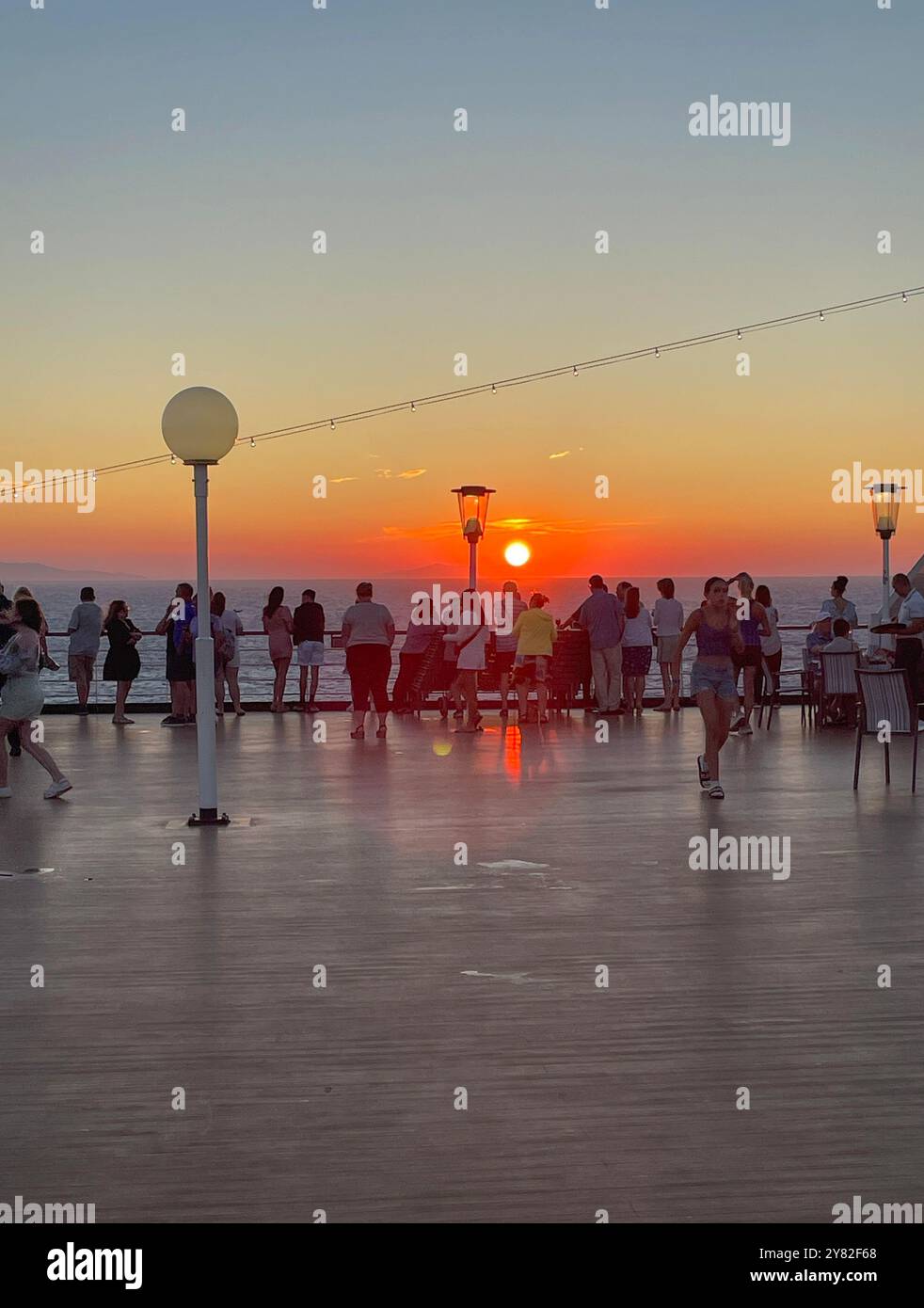 Passagiere auf Deck des Holland America Kreuzfahrtschiffs Oosterdam beobachten einen Sonnenuntergang über Rhodos, Griechenland Stockfoto