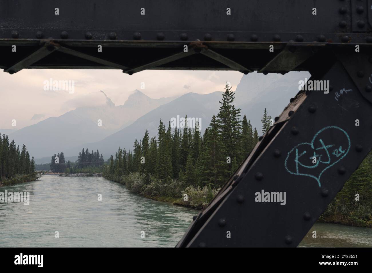 Eiserne Brücke über den Bow River mit Bergen in rauchiger Atmosphäre bei Waldbränden in Canmore, Alberta, Kanadischen Rocky Mountains Stockfoto