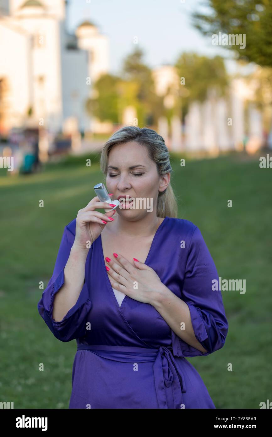 Eine asthmatische Frau, die einen Inhalator nimmt und einen Asthmaanfall hat. Sie hat ein Problem mit Asthma und hält einen Inhalator. Stockfoto