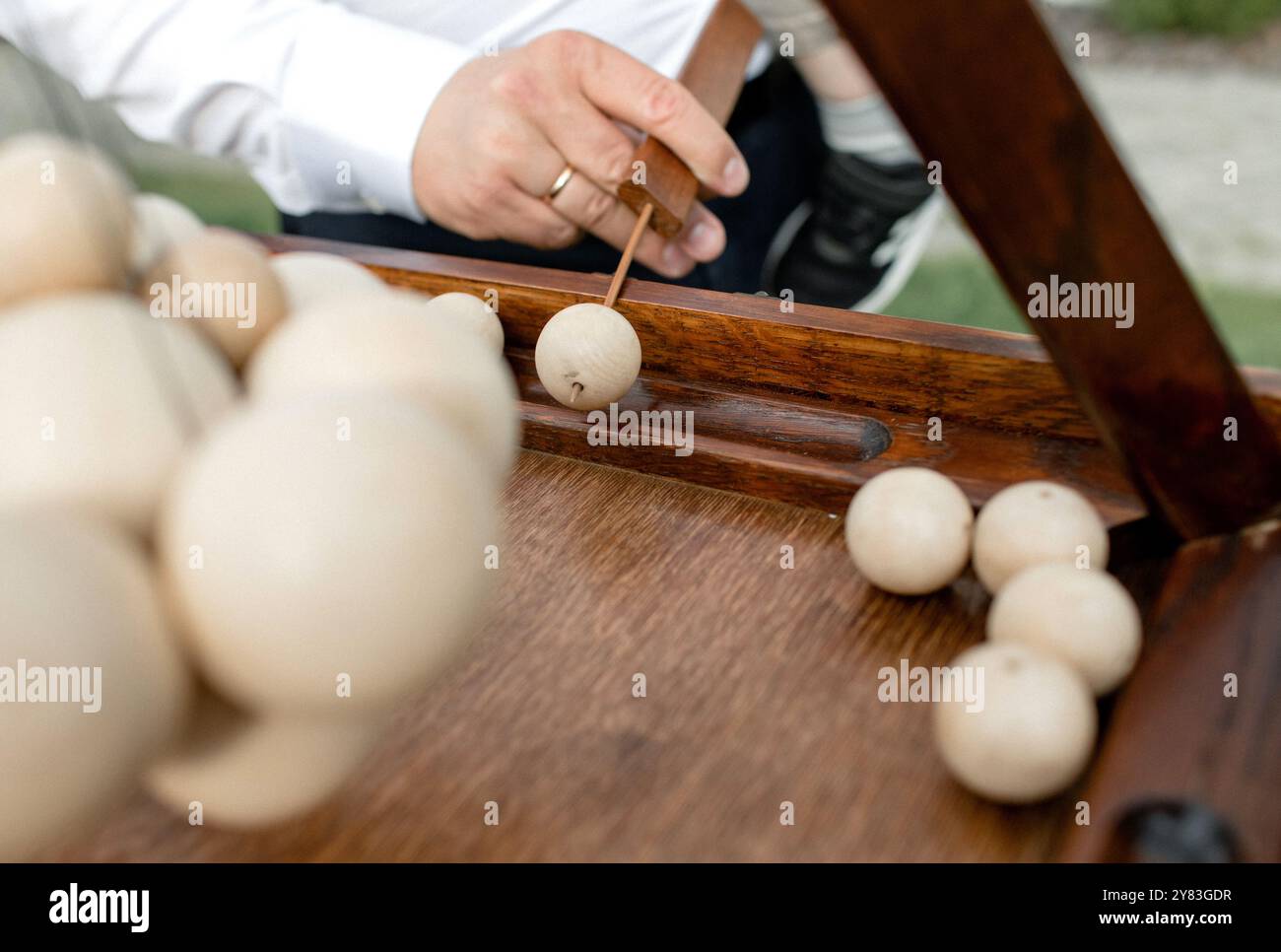 Mit konzentrierter Konzentration wählt ein Spieler sorgfältig eine Holzkugel aus einem klassischen Tischspiel aus, was ein Gefühl von Nostalgie und Kameradschaft weckt Stockfoto