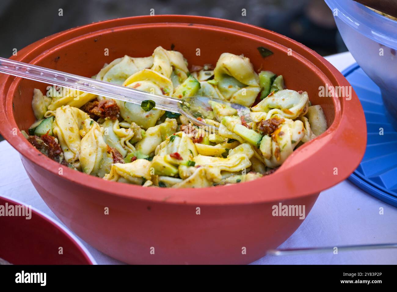 Tortellini-Salat in einer roten Plastikschale, hausgemacht für Picknick oder eine Party im Freien, ausgewählter Fokus, enge Tiefe des Feldes Stockfoto