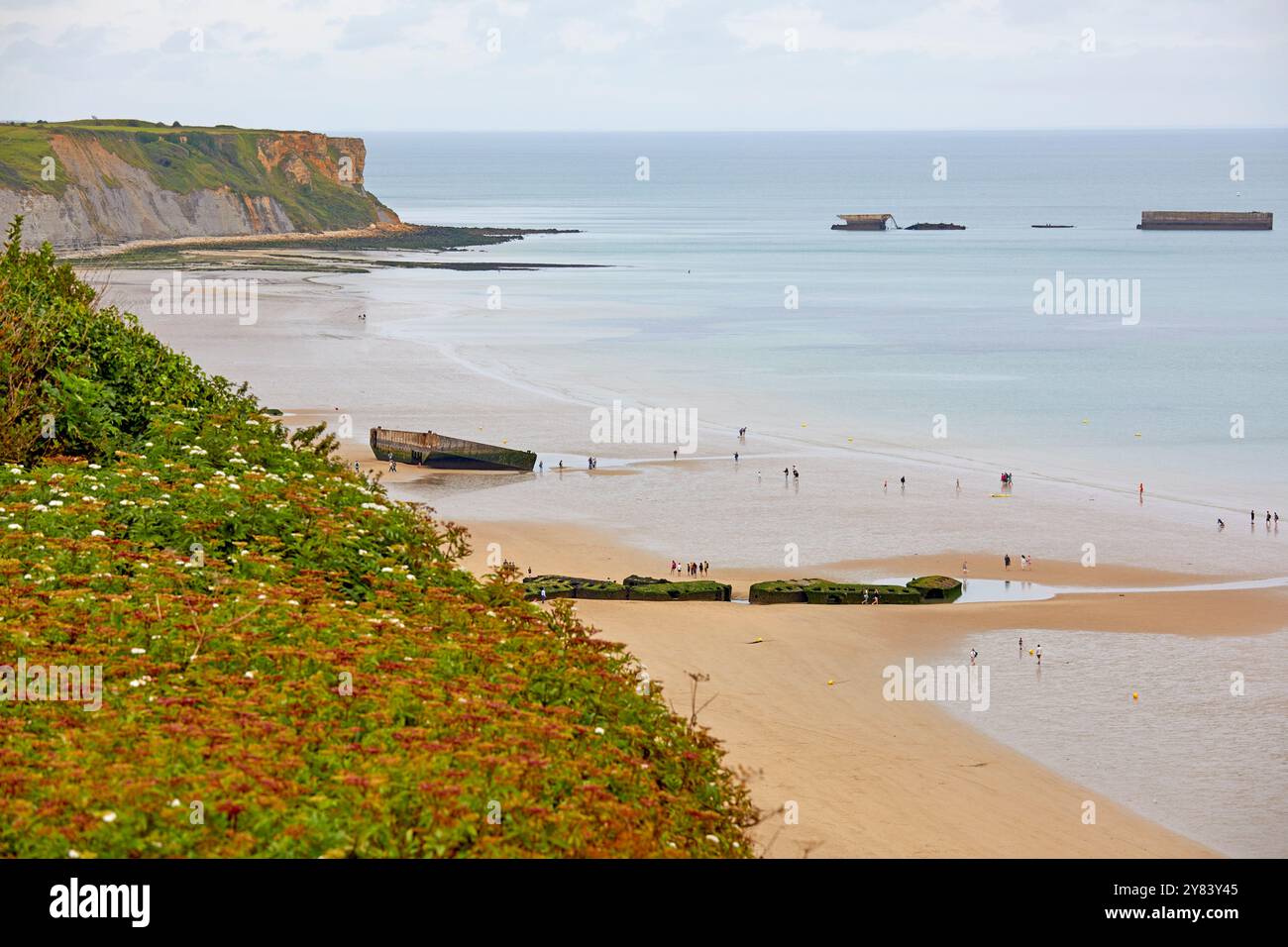 Besucher erkunden die Überreste von Mulberry Harbour, Arromanches Beach, Normandie Frankreich Stockfoto