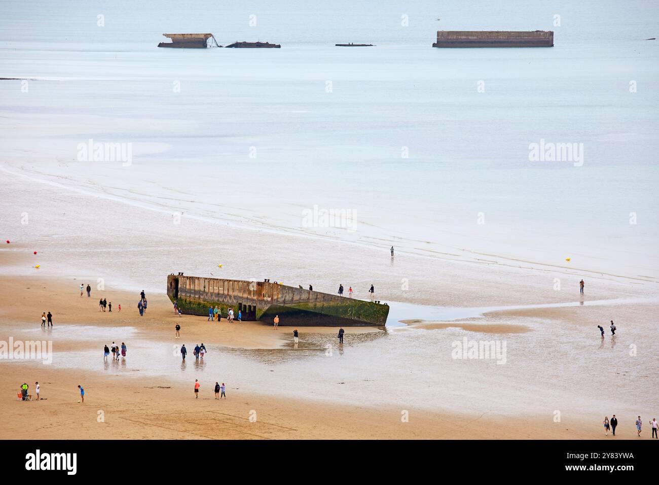 Besucher erkunden die Überreste von Mulberry Harbour, Arromanches Beach, Normandie Frankreich Stockfoto