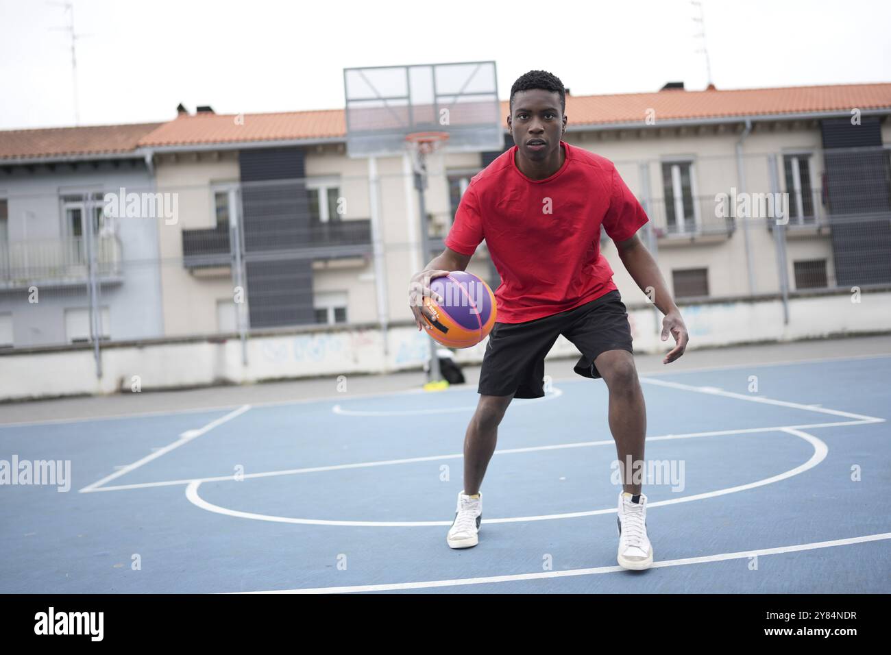 Frontal horizontales Foto eines jungen afrikanischen Basketballspielers, der auf einem Freifeld dribbelt Stockfoto