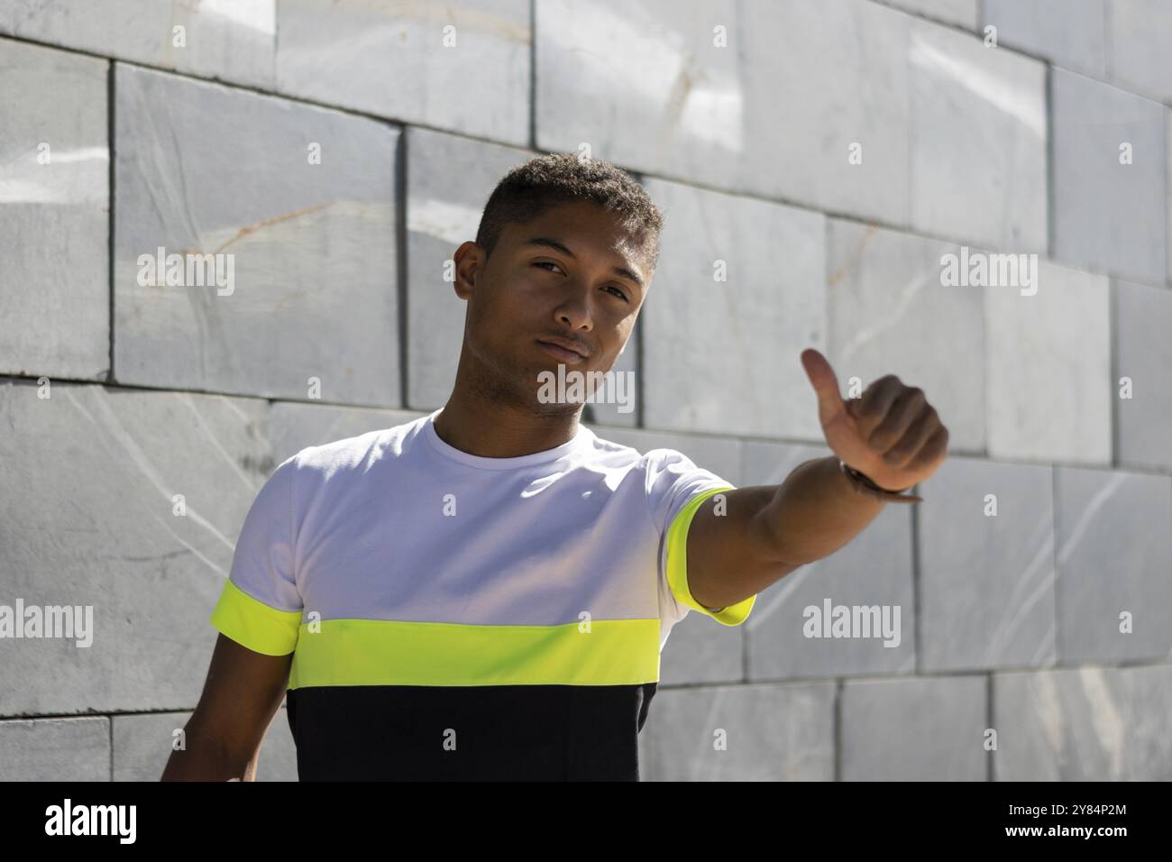Ein junger Mann posiert in die Kamera und macht mit seiner Hand das Symbol „Ich mag“, Porträt Stockfoto