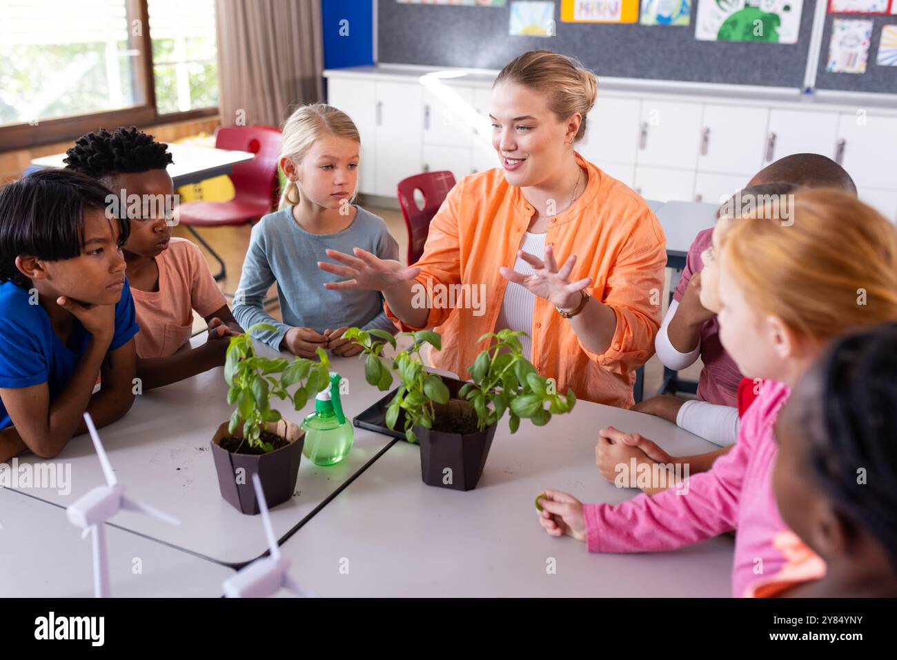 In der Schule erklärt die Lehrerin das Pflanzenwachstum verschiedenen Schülern im Klassenzimmer Stockfoto