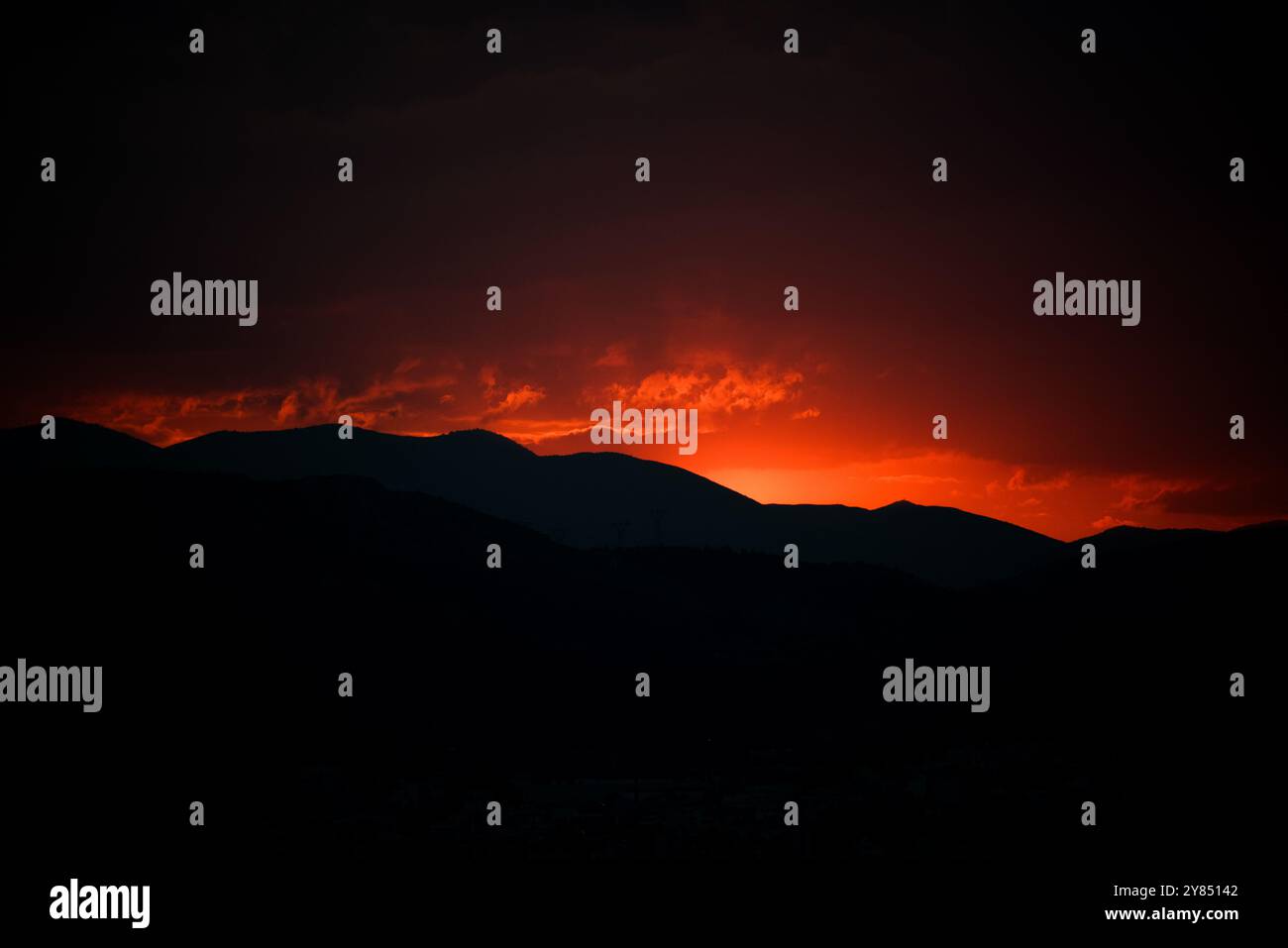 Egaleo Mountain Range Sonnenuntergang Athen Griechenland // ATHEN, Griechenland — Ein dramatischer roter Sonnenuntergang beleuchtet die westliche Skyline von Athen, während die Sonne hinter dem Egaleo Mountain Range absinkt, der die westliche Grenze der Stadt bildet und eine Höhe von 468 Metern (1.535 Fuß) erreicht. Die Silhouetten der Gebäude im Westen Athen bilden ein markantes Stadtprofil vor dem lebendigen karmesinroten und orangen Himmel. Diese mediterrane Sonnenuntergangsszene zeigt die charakteristische Topographie Athens, mit der Stadt eingebettet in ein Becken, umgeben von Bergen, die ihre unverwechselbare Skyline umrahmen. Stockfoto