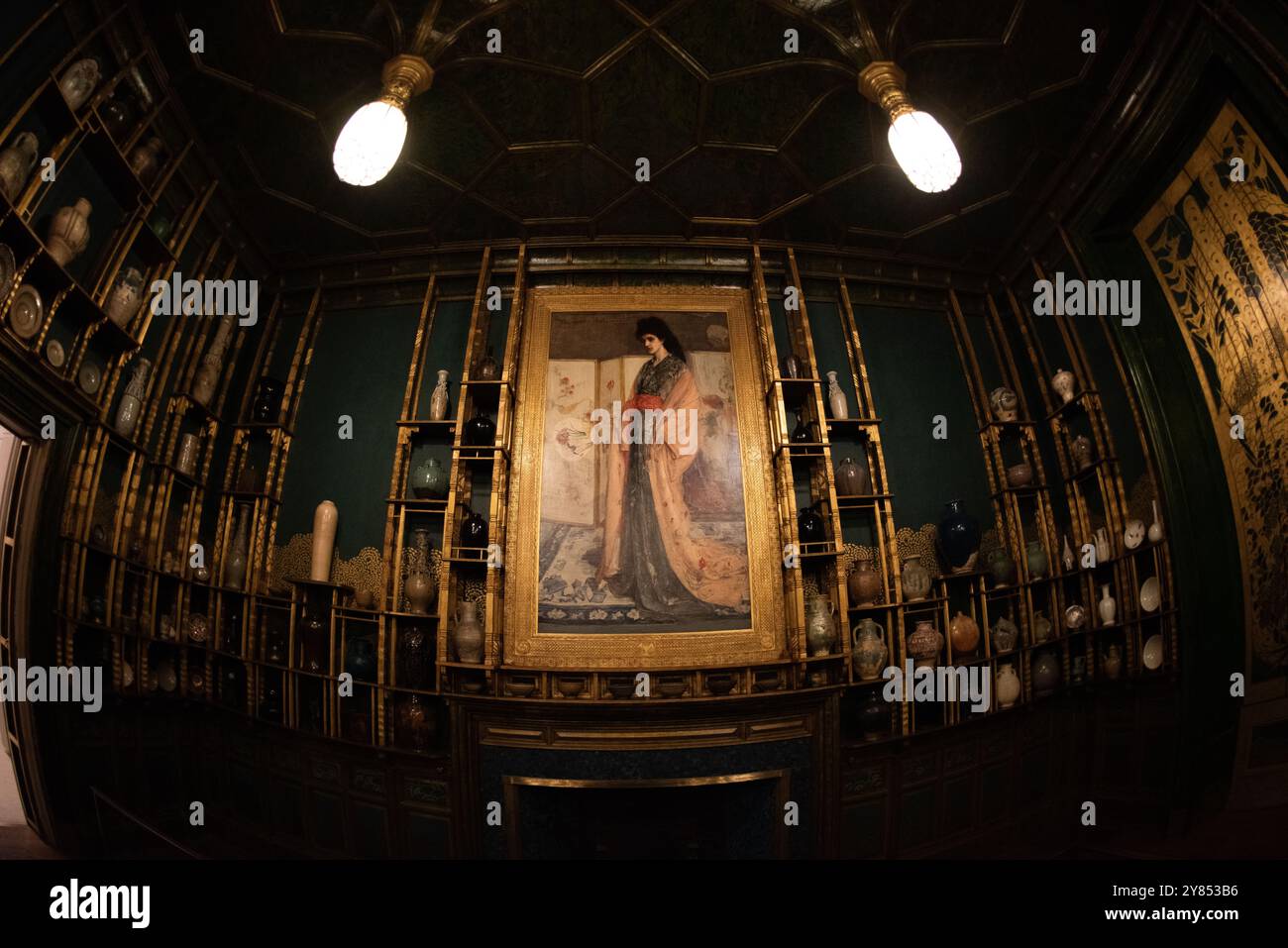 Freer Gallery Peacock Room Washington D.C. // WASHINGTON, D.C. — Rose und Silber: Die Prinzessin aus dem Land des Porzellans von James McNeill Whistler zeigt Christina Spartali, ein anglo-griechisches Modell aus einer prominenten Familie, das in einem Kimono zwischen asiatischen Keramiken und Objekten posiert. Das Gemälde, das als zentraler Mittelpunkt des Pfauensaals dient, fängt die Mode des Japonismus aus dem 19. Jahrhundert durch Spartalias kontemplative Pose und Fächer ein. Obwohl Whistler das Werk nicht als wörtliches Porträt vorhatte, spiegelt die Komposition seine Auseinandersetzung mit imaginären östlichen Themen wider, die während der Aesthet populär waren Stockfoto