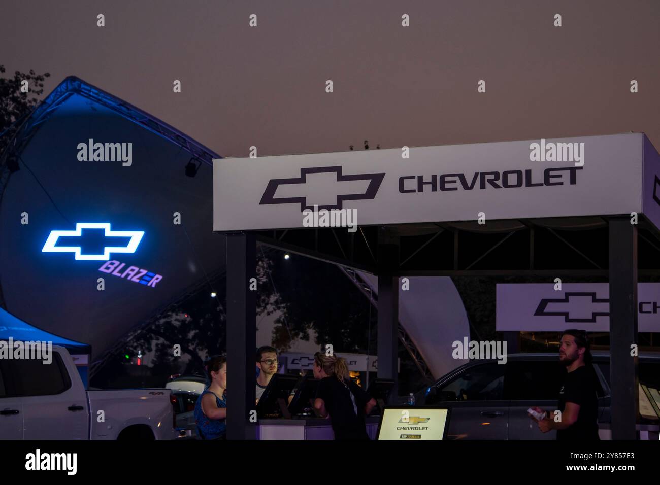 Falcon Heights, Minnesota. Kunden sprechen am Abend auf der Minnesota State Fair mit einem Vertriebsmitarbeiter im Chevrolet-Händlerbetrieb. Stockfoto