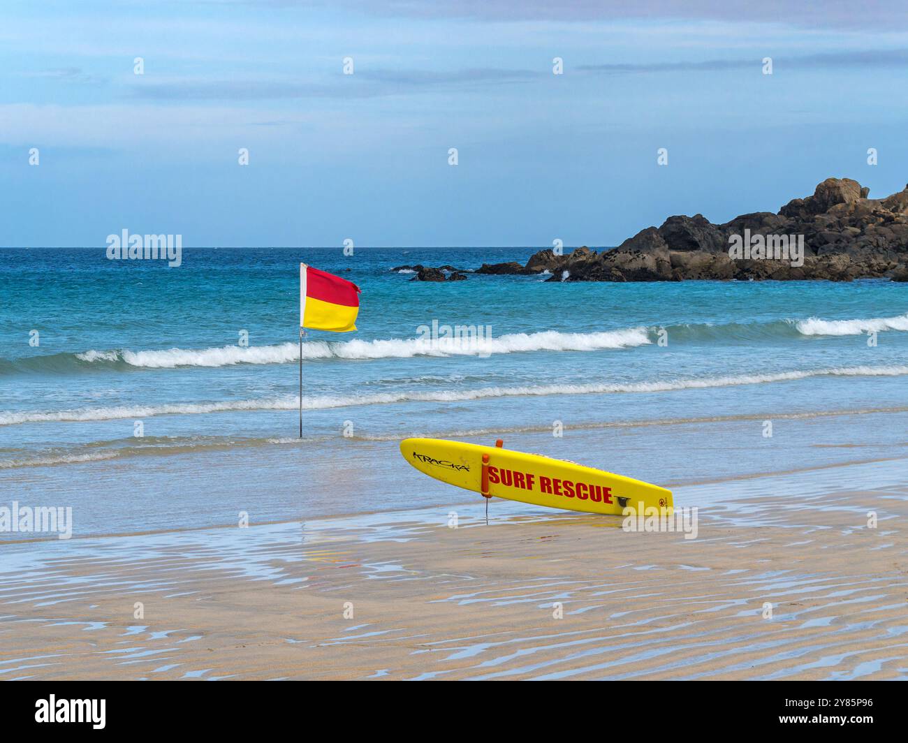 Gelbes Surfbrett und gelbe und rote Rettungsfahne am Porthmeor Beach, St. Ives, Cornwall, England, Großbritannien Stockfoto