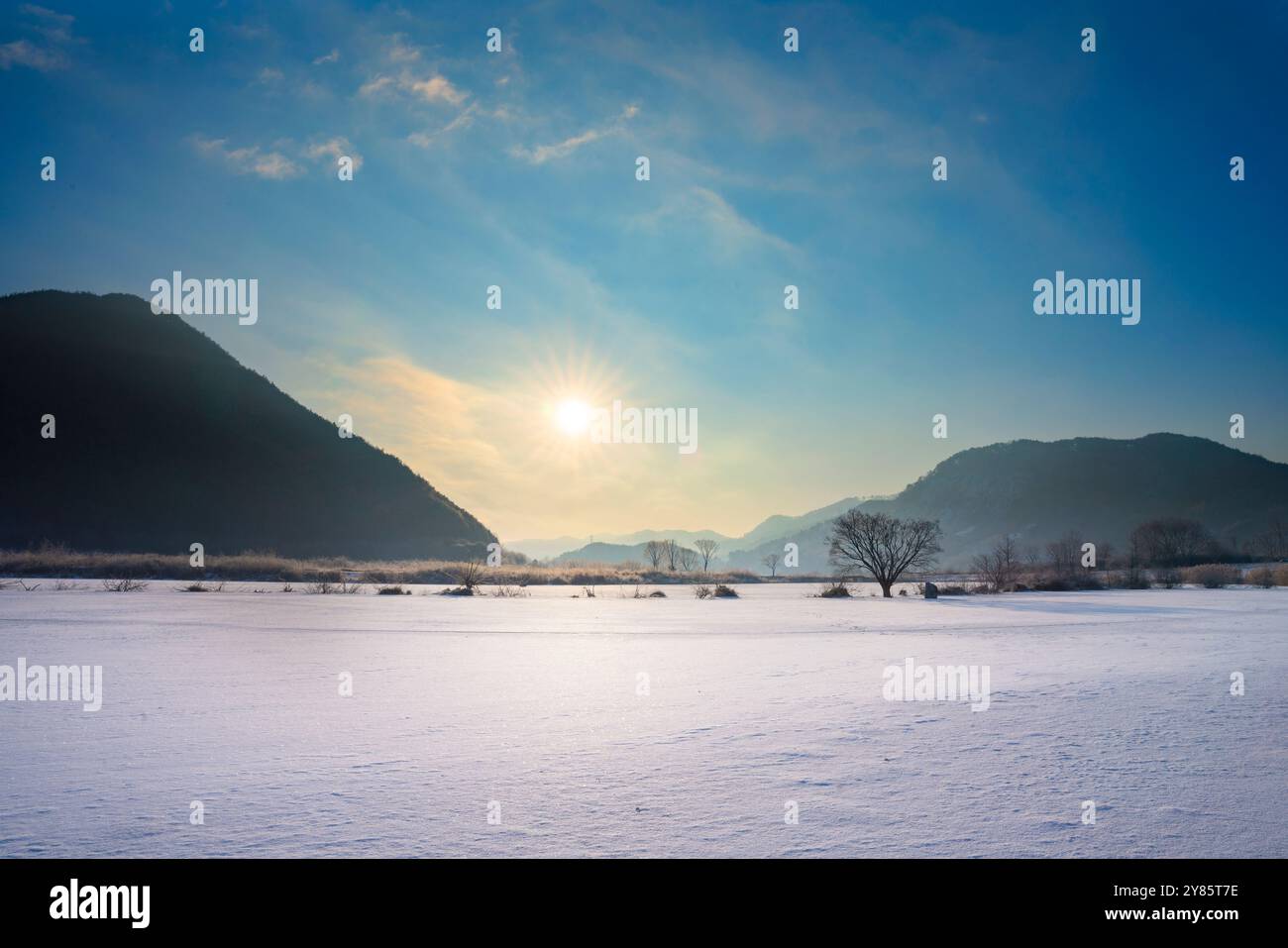 Ein Wintermorgen über einem gefrorenen See in Jinan, Jeollabuk-Do, mit Sonnenaufgang über dem Horizont, ein sanftes goldenes Licht über die eisige Oberfläche. Stockfoto