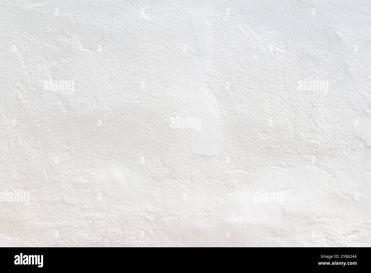 Vorderansicht einer sauberen und leeren, verputzten Wand, die an sonnigem Tag in weiß gestrichen ist. Abstrakter, hochauflösender Texturhintergrund mit Kopierraum. Stockfoto