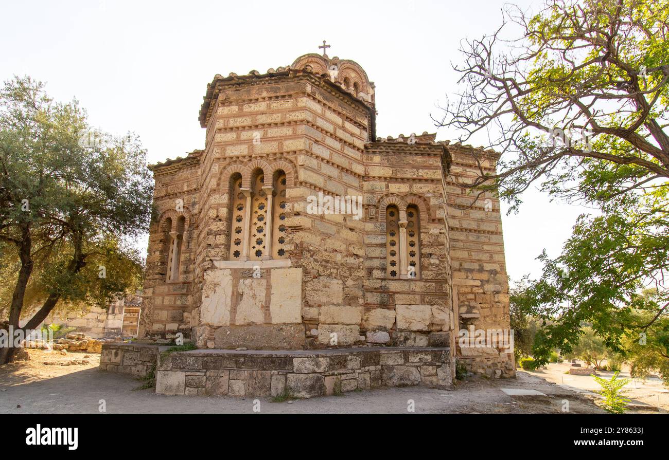 Alte Steinkirche im byzantinischen Stil mit Kuppeldach und Kreuz auf der Spitze, umgeben von Bäumen und Pfad in Athen, Griechenland. Architektonische Fotos im Freien Stockfoto