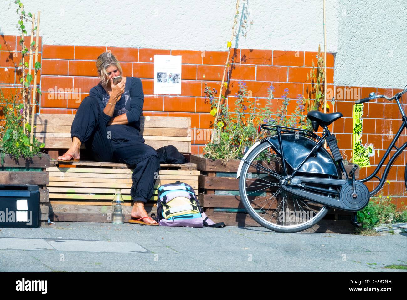 Lifestyle Freizeit Alltag, alleinstehende Frau Frau allein, sitzend auf Holzbank, Handy, Kreuzberg Berlin Stockfoto