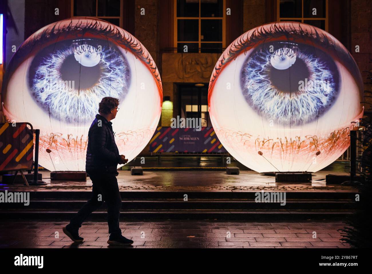 Essen, NRW, Deutschland. Oktober 2024. Besucher interagieren mit der Installation „Oculus“ der Künstler H:E:M (Italien) außerhalb des Grillo-Theaters. Zwei riesige Kugeln leuchten in Form von zwei Augen, die in den Himmel blicken. Eröffnungsabend des jährlichen Essen Light Festivals mit 16 großformatigen Lichtinstallationen in der ganzen Stadt. Das Festival ist frei zu sehen und findet jeden Abend von Sonnenuntergang bis 23 Uhr vom 2. Bis 13. Oktober 2024 statt. Quelle: Imageplotter/Alamy Live News Stockfoto